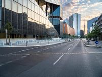 an empty street with some buildings in the background on a city street during sunset,