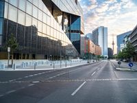 an empty street with some buildings in the background on a city street during sunset,