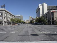 the city street is empty except for people to cross it with a traffic light in the middle