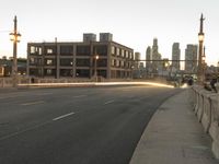 an empty city street with a long bridge crossing into it at dusk time, and tall building near side with lights