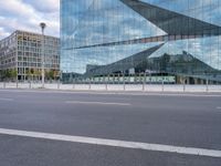 view of an empty city street, with a tall glass building and a parking meter