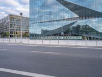 view of an empty city street, with a tall glass building and a parking meter