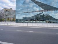 view of an empty city street, with a tall glass building and a parking meter