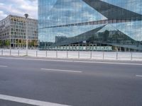 view of an empty city street, with a tall glass building and a parking meter