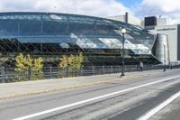 an empty city street near a metal fence with white lines on it, with a green building in the background