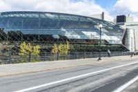 an empty city street near a metal fence with white lines on it, with a green building in the background