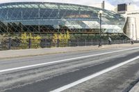 an empty city street near a metal fence with white lines on it, with a green building in the background