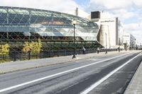 an empty city street near a metal fence with white lines on it, with a green building in the background