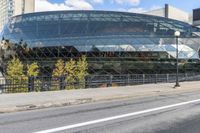 an empty city street near a metal fence with white lines on it, with a green building in the background