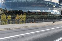 an empty city street near a metal fence with white lines on it, with a green building in the background