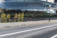 an empty city street near a metal fence with white lines on it, with a green building in the background