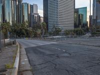 an empty city street with high rise buildings in the background and cars on the roadway