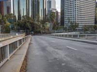 an empty city street with high rise buildings in the background and cars on the roadway