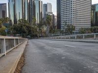 an empty city street with high rise buildings in the background and cars on the roadway