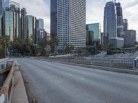 an empty city street with high rise buildings in the background and cars on the roadway