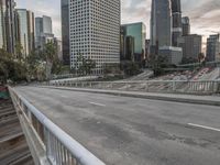 an empty city street with high rise buildings in the background and cars on the roadway