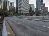 an empty city street with high rise buildings in the background and cars on the roadway