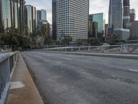 an empty city street with high rise buildings in the background and cars on the roadway
