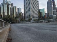 an empty city street with high rise buildings in the background and cars on the roadway