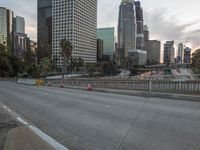an empty city street with high rise buildings in the background and cars on the roadway