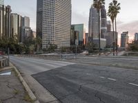 an empty city street with high rise buildings in the background and cars on the roadway