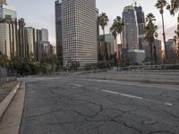 an empty city street with high rise buildings in the background and cars on the roadway