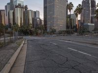an empty city street with high rise buildings in the background and cars on the roadway