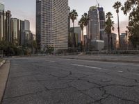 an empty city street with high rise buildings in the background and cars on the roadway