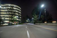 an empty city street lit by the lights of a nearby building at night time with motion blur