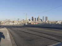 an empty city street with the view of a city on one side of it, and traffic lights in the other side