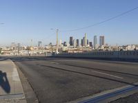 an empty city street with the view of a city on one side of it, and traffic lights in the other side