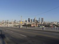 an empty city street with the view of a city on one side of it, and traffic lights in the other side