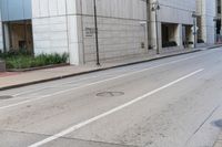 a empty city street with a man walking across it with a hat on his head