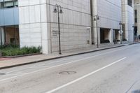 a empty city street with a man walking across it with a hat on his head