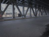 an empty city street beneath a large metal bridge with graffiti covering it's walls