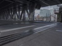 an empty city street beneath a large metal bridge with graffiti covering it's walls