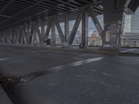 an empty city street beneath a large metal bridge with graffiti covering it's walls