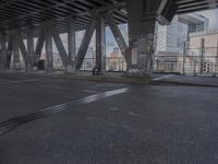 an empty city street beneath a large metal bridge with graffiti covering it's walls