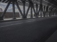 an empty city street beneath a large metal bridge with graffiti covering it's walls