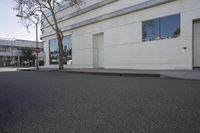 a city street is empty and a stop sign is near a building with several glass windows