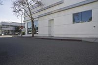 a city street is empty and a stop sign is near a building with several glass windows