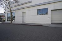 a city street is empty and a stop sign is near a building with several glass windows