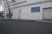 a city street is empty and a stop sign is near a building with several glass windows