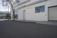 a city street is empty and a stop sign is near a building with several glass windows