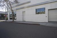 a city street is empty and a stop sign is near a building with several glass windows