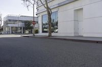 a city street is empty and a stop sign is near a building with several glass windows