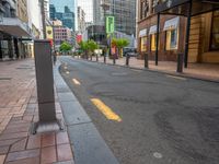 an empty city street lined with tall buildings and sidewalk lights on a sunny day a traffic light near a black paved street