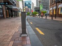 an empty city street lined with tall buildings and sidewalk lights on a sunny day a traffic light near a black paved street