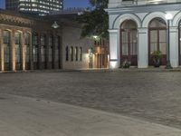 the sidewalk is empty outside the buildings at night during the day time time period, with a city street in the background