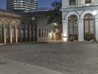 the sidewalk is empty outside the buildings at night during the day time time period, with a city street in the background